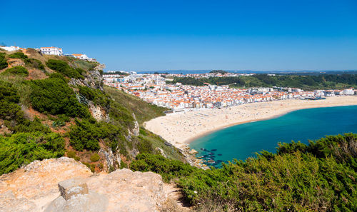 High angle view of townscape by sea against clear blue sky