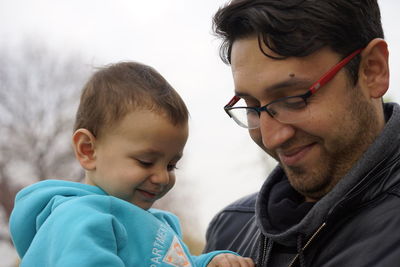 Close-up portrait of boy and son against sky