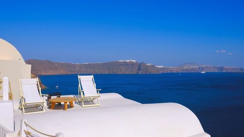 Chairs on beach against blue sky