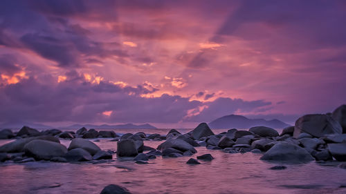 Rocks on beach against sky during sunset