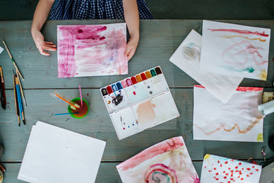 Young girl finishing a bright pink abstract painting from above