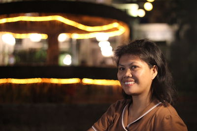 Close-up of young woman smiling at night