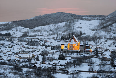 Snow covered houses and fortified church against  mountain and sky during winter