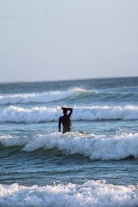 Rear view of man standing in sea against sky