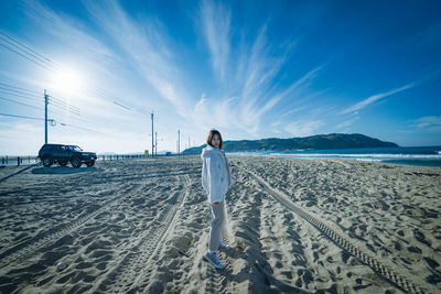 Rear view of woman standing on beach against sky
