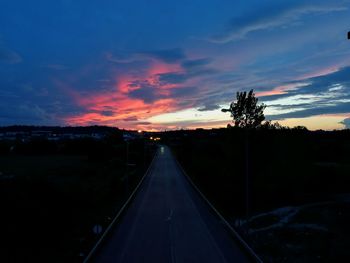 Road amidst trees against sky at night