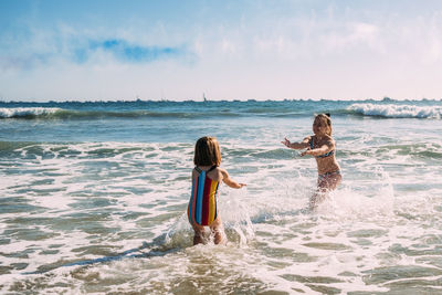 Sisters playing and splashing in the pacific ocean