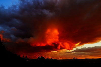 Silhouette landscape against dramatic sky at sunset