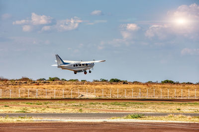 Airplane flying over land against sky