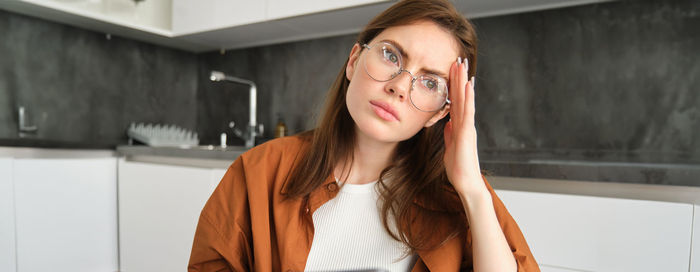 Portrait of young woman standing against wall