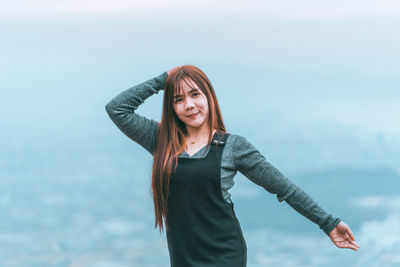 Portrait of young woman standing against sky