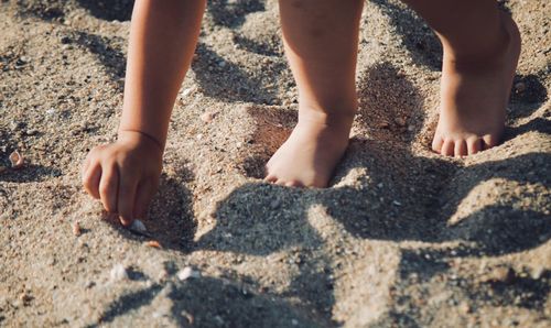 Low section of child on sand at beach