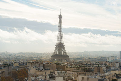 Communications tower in city against sky