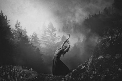 Young woman posing while standing on mountain during foggy weather