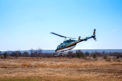 Helicopter on landscape against clear blue sky