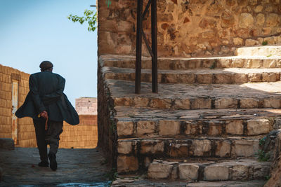 Full length rear view of man walking on staircase against building