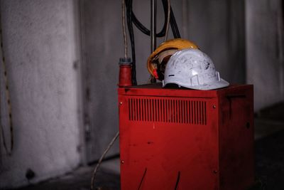 Person holding red umbrella against wall