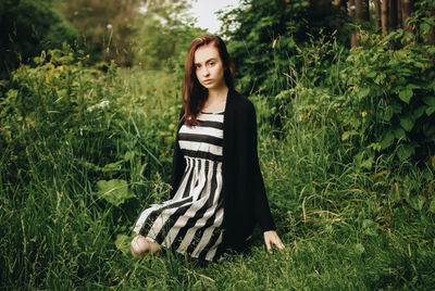 Young woman crouching on grassy field