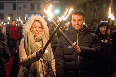 Portrait of smiling young woman standing against illuminated fire at night