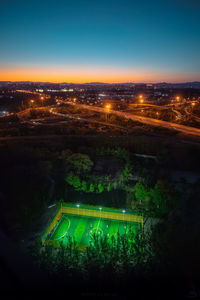 Aerial view of illuminated cityscape against sky during sunset