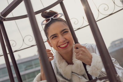 Portrait of smiling woman in sunglasses against gate