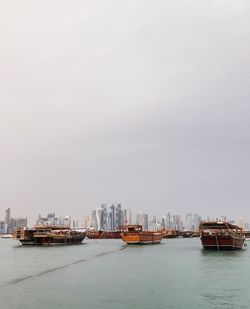 Boats sailing in sea against clear sky