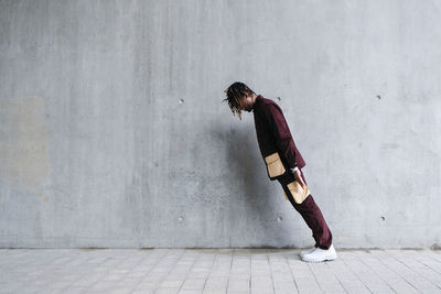 Young man leaning in front of concrete wall