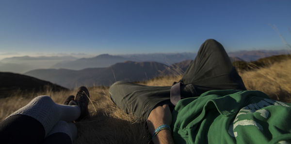 Rear view of people sitting on mountain against sky