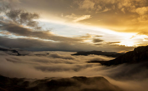 Scenic view of mountains against dramatic sky during sunset