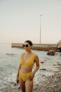 Young woman standing at beach against clear sky