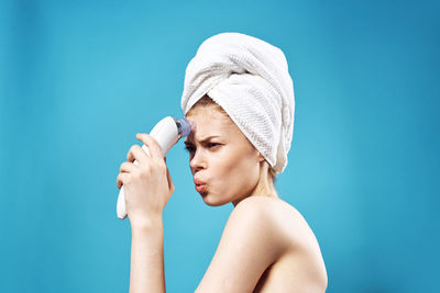 Young woman massaging face against blue background