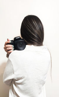 Side view of woman photographing with camera against white background