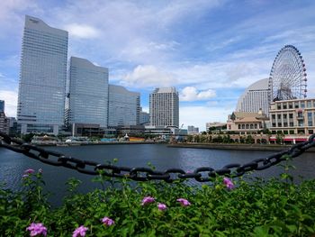 View of buildings by river against cloudy sky