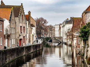 Bridge over canal amidst buildings against sky