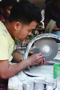 Side view of man with grinder working at workshop