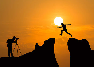 Silhouette people photographing against sky during sunset