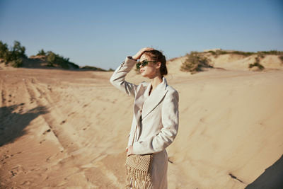 Young woman standing against sky