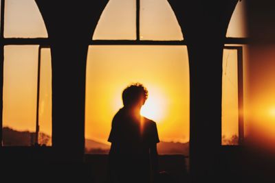 Silhouette couple standing in corridor against romantic sky at sunset