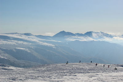 People on snowcapped mountains against sky during sunset