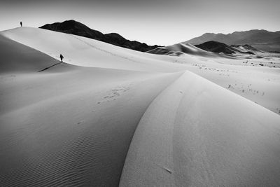 Scenic view of sand dunes and mountains against sky