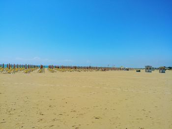 Group of people on beach against clear blue sky