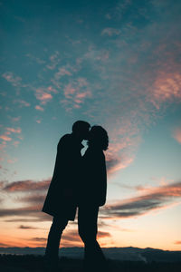 Silhouette of couple kissing at sunset