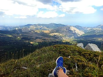 Low section of person on mountain against sky