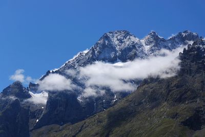 Low angle view of snowcapped mountains against blue sky