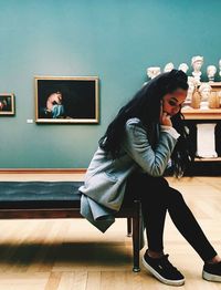 Full length of young woman sitting on seat at home