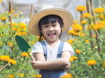 Portrait of cute girl standing by flowering plants on field
