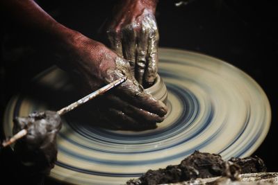 Cropped image of man shaping earthenware on pottery wheel at workshop