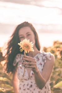 Midsection of woman standing by flowering plant