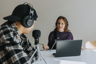 Young man and woman talking during podcast in classroom
