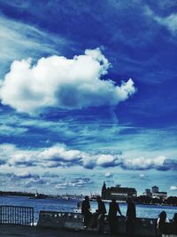 People on beach against sky in city